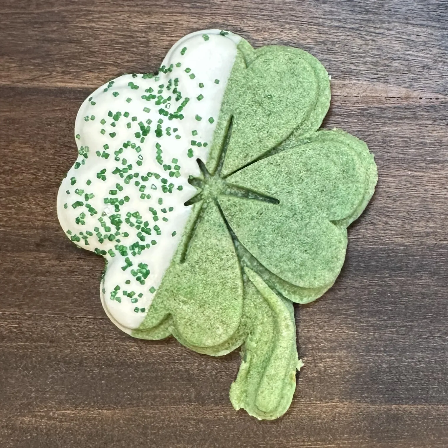 White chocolate dipped shamrock cookie with green sprinkles
